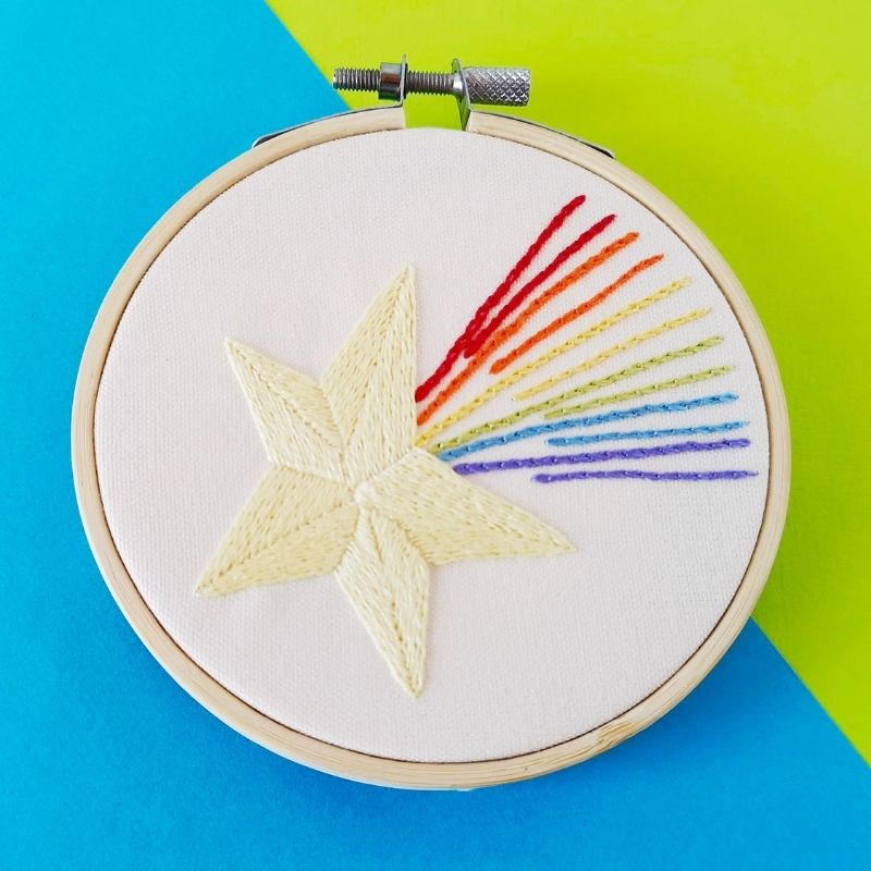 Cuadro bordado a mano con estrella arco iris enmarcado en un aro