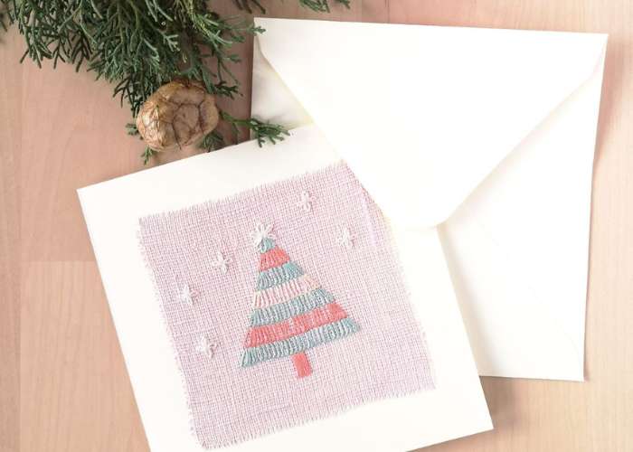 Postal con bordado de árbol de Navidad sobre lino rosa, sobre blanco y piña