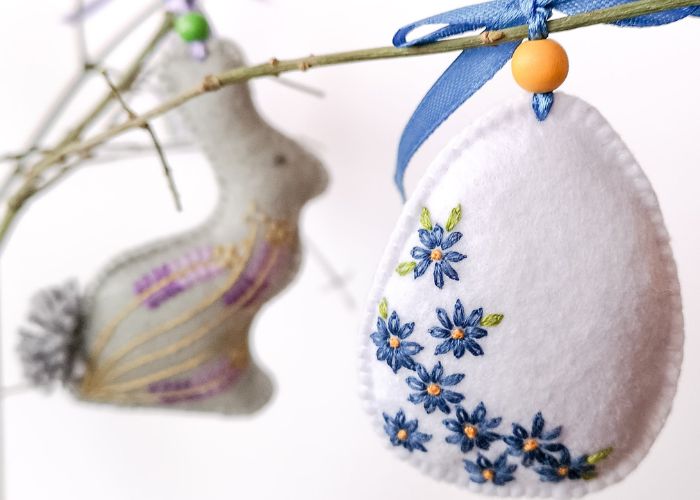 Huevo de Pascua y adornos de fieltro de conejo en una rama