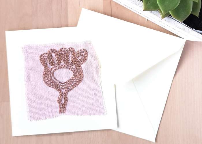 Tarjeta vegetal abstracta bordada a mano con punto de cadeneta sobre tela de lino rosa