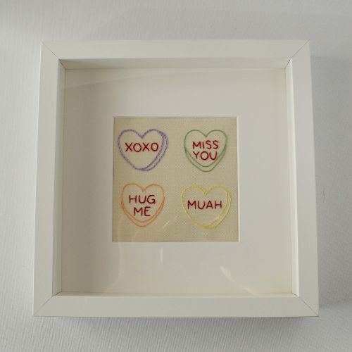 Bordado de corazones de caramelo enmarcado en un marco de fotos cuadrado