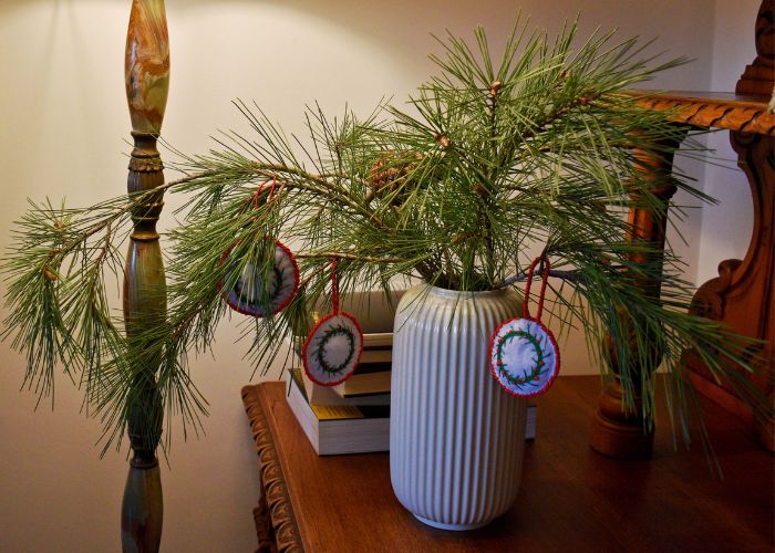 Rama de pino en un jarrón decorado con adornos hechos a mano