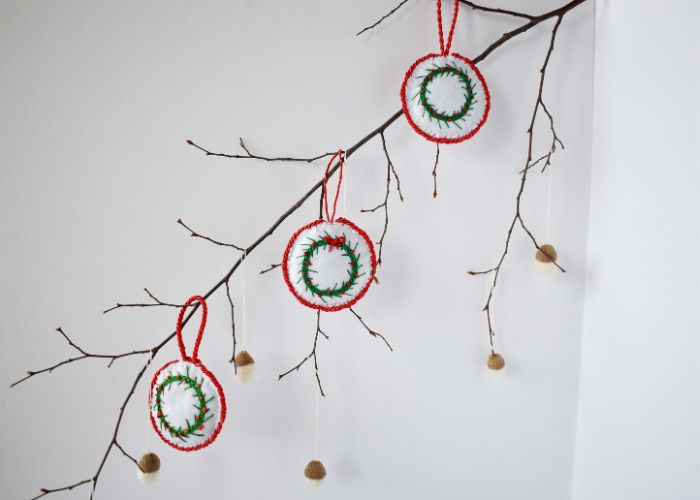 Rama de árbol decorada con adornos DIY y bellotas