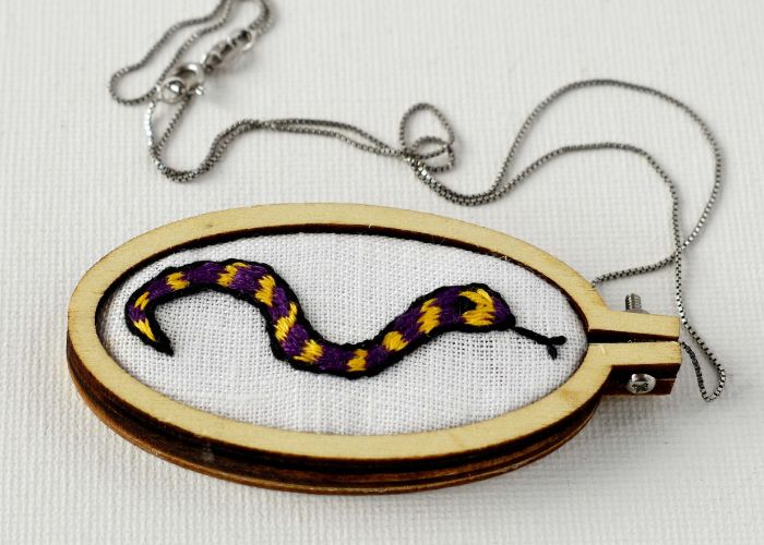 Colgante con un bordado de serpiente enmarcado en un mini aro